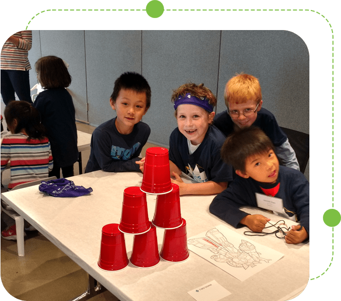 A group of kids sitting at a table with red cups.
