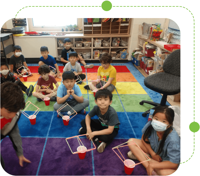 A group of children sitting on the floor in front of cups.