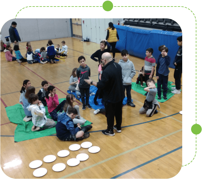 A group of people sitting on the floor with frisbees.