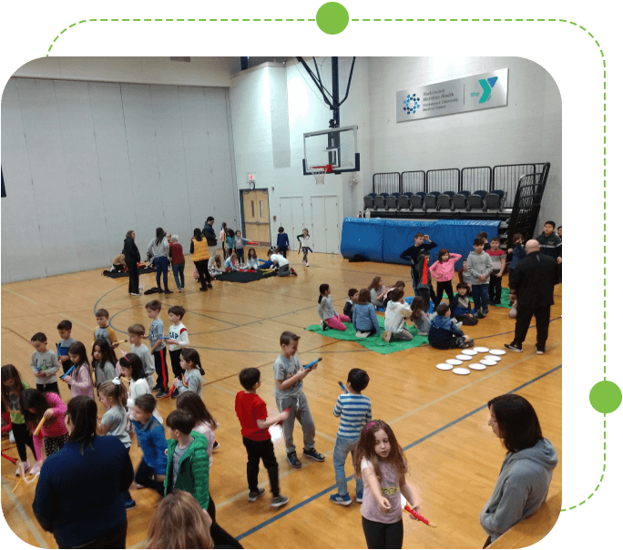 A group of children standing in the middle of an indoor gymnasium.