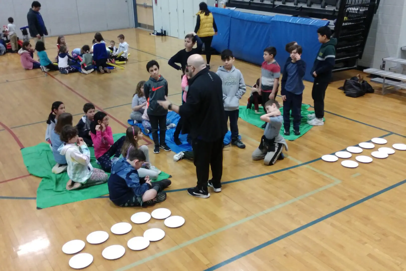 A group of people sitting on the floor with frisbees.