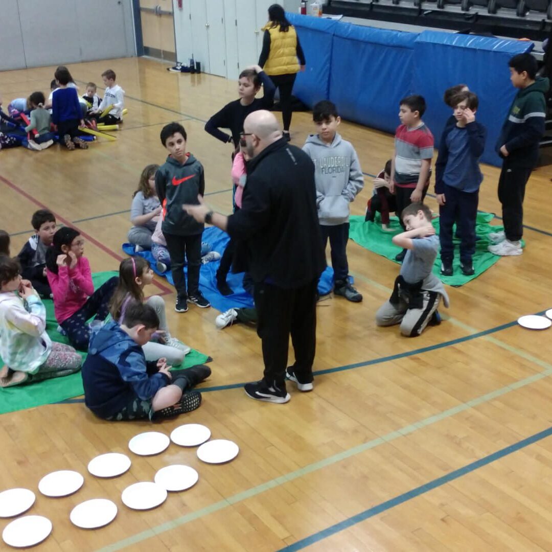 A group of people sitting on the floor with frisbees.